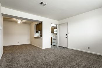 A spacious living area with a kitchenette and a doorway leading to another room.